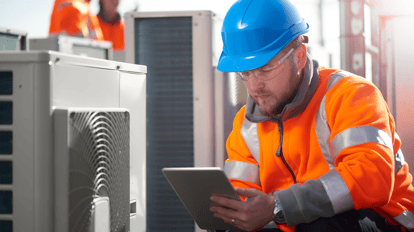 maintenance in Hospitality Industry - man in blue hard hat and orange jacket checking air-con unit
